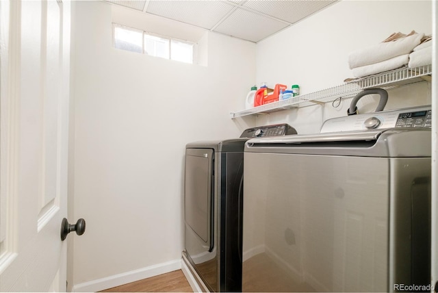 laundry room with baseboards, light wood-style floors, laundry area, and washing machine and clothes dryer