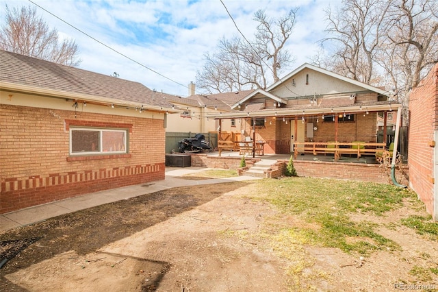 exterior space with a patio, brick siding, and roof with shingles