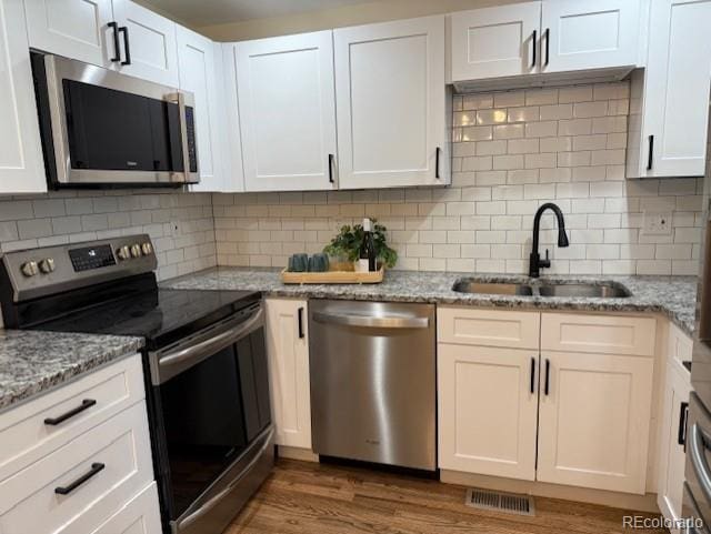 2510 Kenton, Aurora, CO 80010 - kitchen with appliances with stainless steel finishes, white cabinets, wood finished floors, and tasteful backsplash