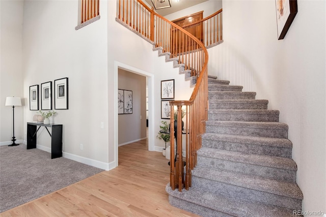 staircase featuring wood-type flooring and a towering ceiling