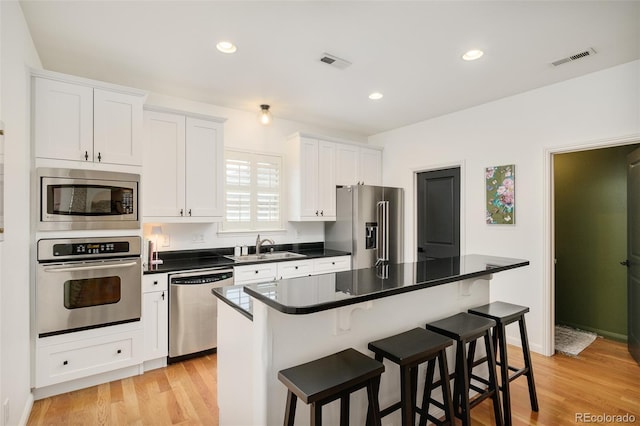 kitchen with appliances with stainless steel finishes, a kitchen island, white cabinetry, and a kitchen bar