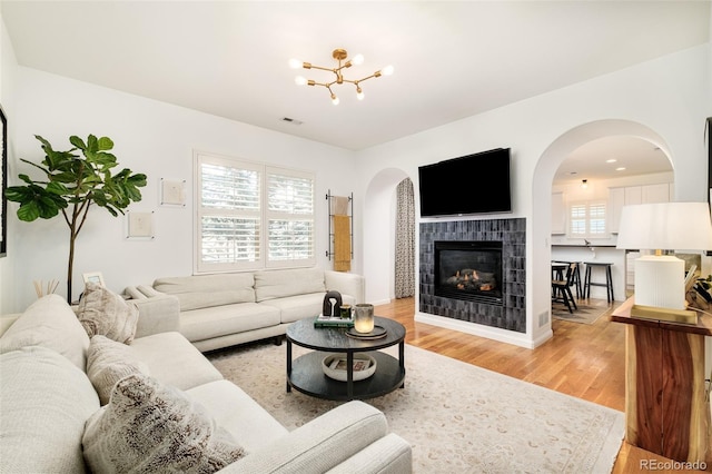 living room with visible vents, plenty of natural light, light wood-style flooring, and a fireplace