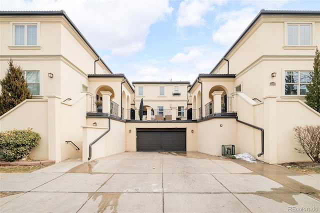 exterior space with a garage, concrete driveway, a balcony, and stucco siding