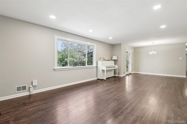 unfurnished living room with dark wood-style flooring, a chandelier, baseboards, and recessed lighting