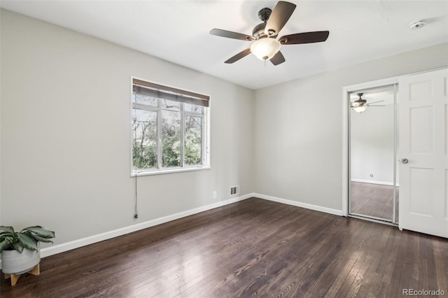 unfurnished bedroom featuring dark wood-type flooring, baseboards, a closet, and ceiling fan