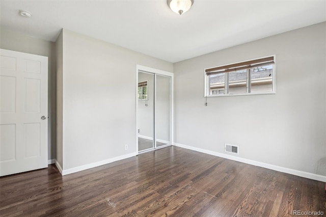 unfurnished bedroom with wood finished floors, a closet, and baseboards