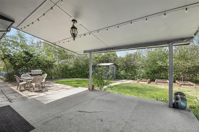 view of patio / terrace featuring outdoor dining area, an outdoor structure, a storage shed, a vegetable garden, and view of scattered trees