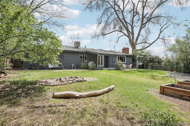 rear view of house with a chimney, cooling unit, and a garden