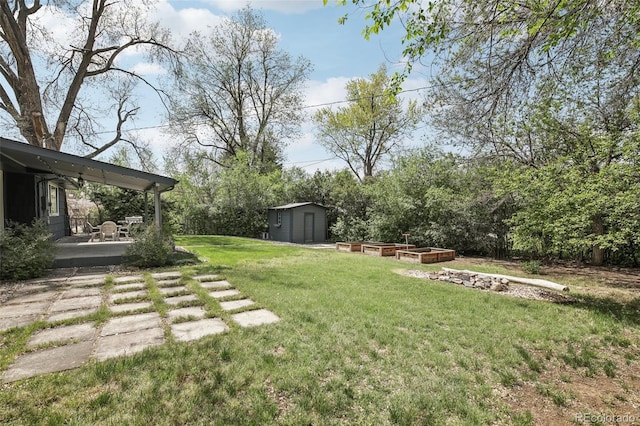 view of green lawn featuring a shed, an outbuilding, a patio, and a garden