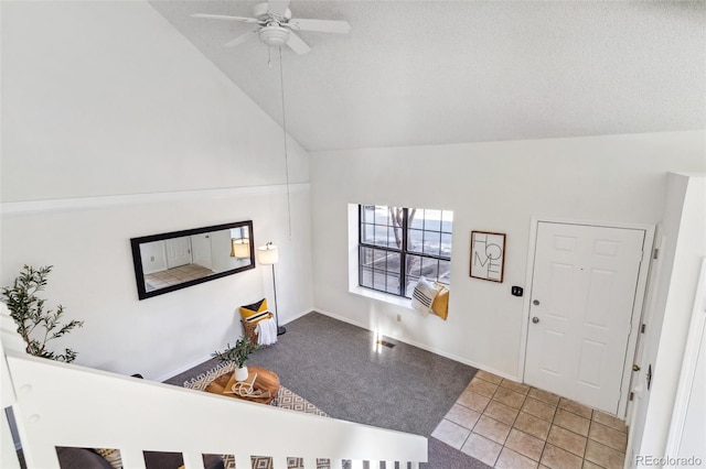 tiled foyer with ceiling fan, a textured ceiling, and high vaulted ceiling