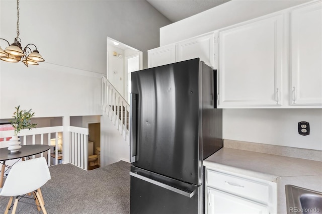 kitchen with pendant lighting, fridge, white cabinetry, and high vaulted ceiling