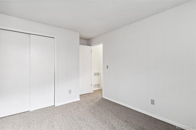 unfurnished bedroom featuring a textured ceiling, a closet, and carpet floors