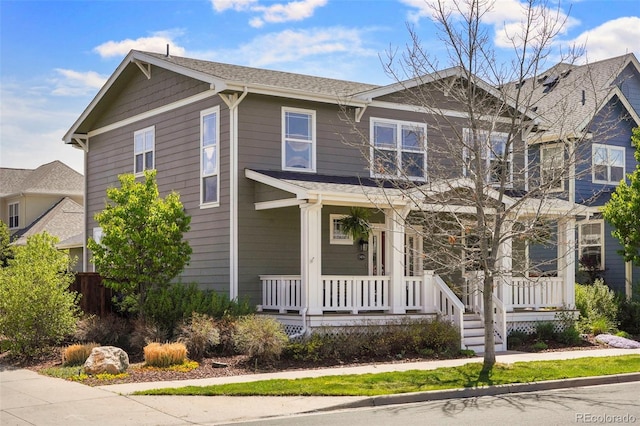 craftsman inspired home featuring covered porch and roof with shingles