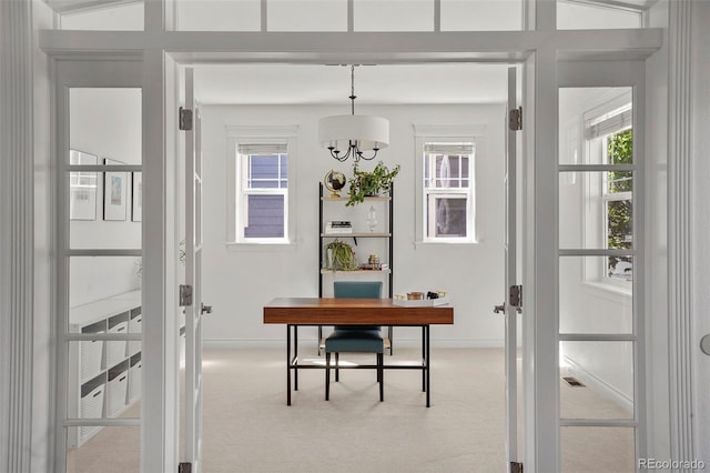 carpeted office space with baseboards and a chandelier