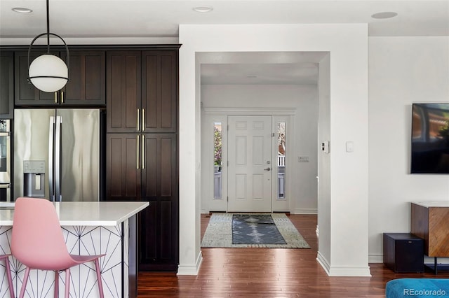 kitchen featuring dark brown cabinets, stainless steel appliances, dark wood finished floors, baseboards, and light countertops