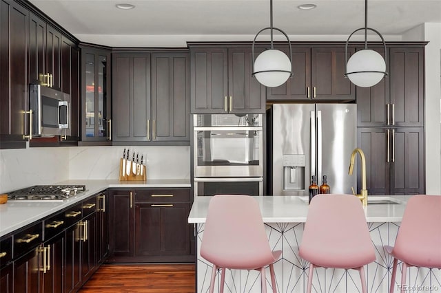 kitchen with light countertops, a kitchen breakfast bar, appliances with stainless steel finishes, and glass insert cabinets