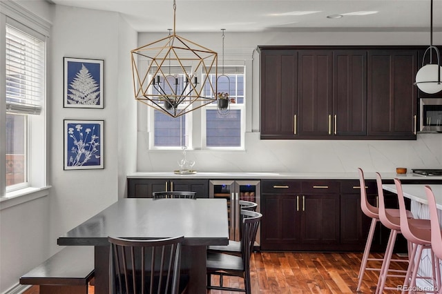 dining room featuring dark wood finished floors, wine cooler, and a notable chandelier