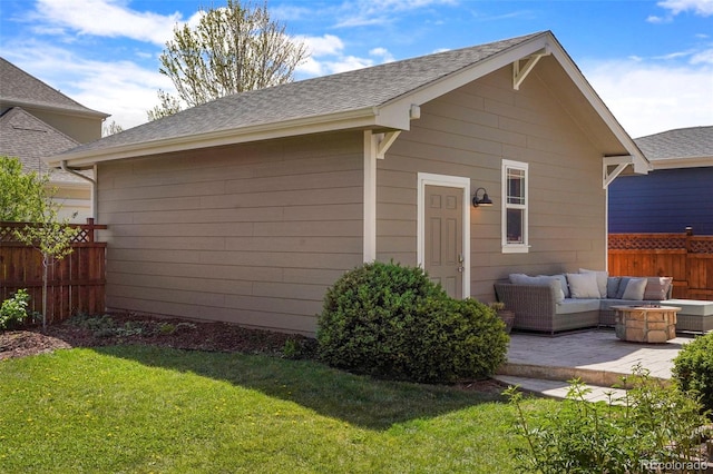 exterior space featuring roof with shingles, fence, a patio area, a lawn, and an outdoor living space with a fire pit