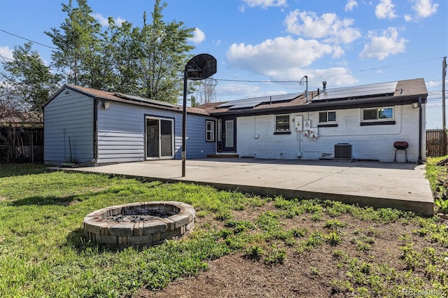 8641 Lowell Blvd, Westminster, CO 80031 - back of house with a fire pit, a patio, roof mounted solar panels, brick siding, and central AC unit