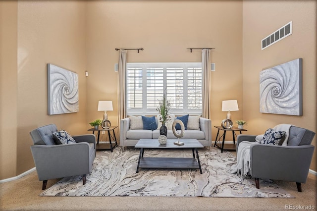 carpeted living area with visible vents, baseboards, and a towering ceiling
