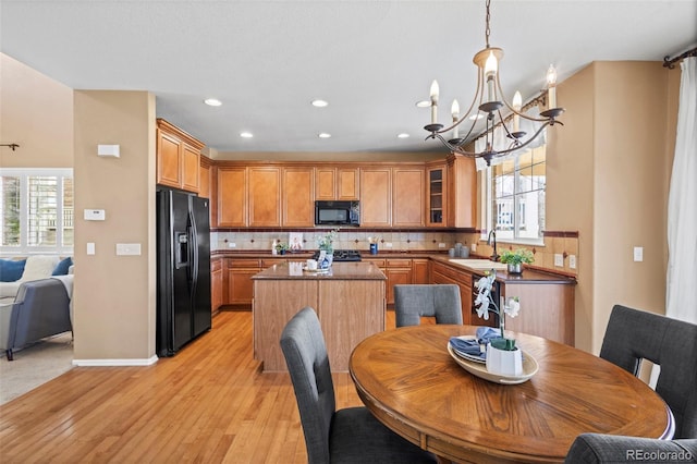 dining room with recessed lighting, a notable chandelier, a wealth of natural light, and light wood-style flooring