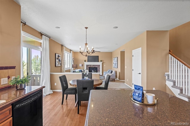 dining area featuring a brick fireplace, a chandelier, baseboards, light wood-type flooring, and stairway