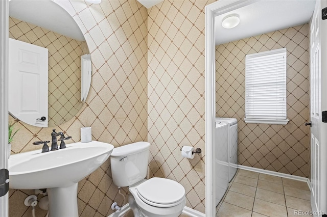 bathroom with independent washer and dryer, tile walls, a sink, tile patterned floors, and toilet