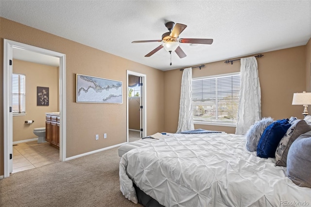 bedroom featuring baseboards, light colored carpet, multiple windows, and ensuite bath