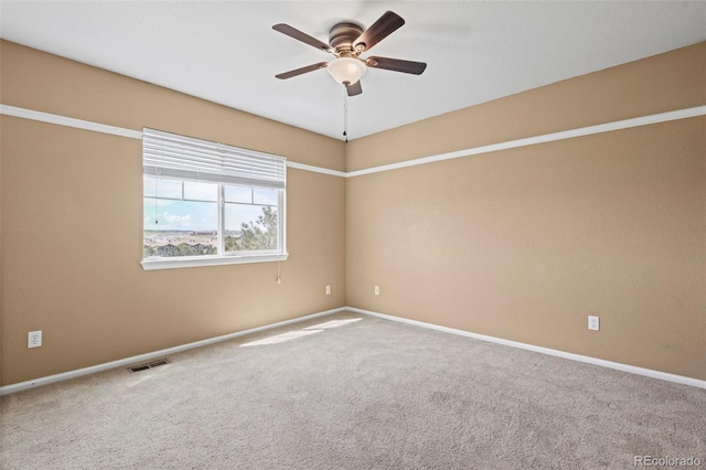 carpeted spare room featuring visible vents, a ceiling fan, and baseboards