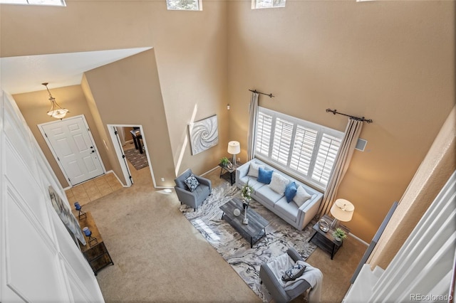 living area featuring baseboards, plenty of natural light, carpet flooring, and a towering ceiling
