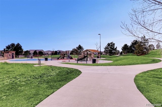 view of property's community featuring a lawn and playground community