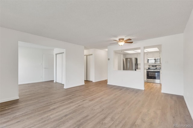 unfurnished living room featuring a ceiling fan, baseboards, a textured ceiling, and light wood finished floors