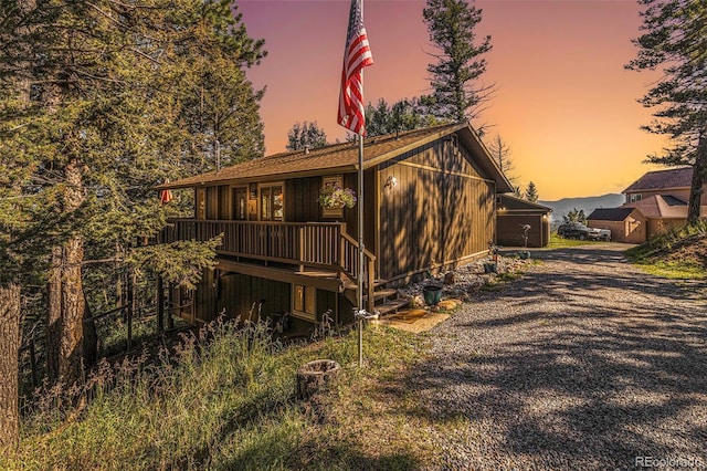 rear view of house featuring driveway and a deck