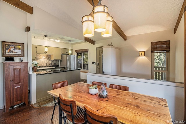 dining space with vaulted ceiling with beams and dark wood-type flooring