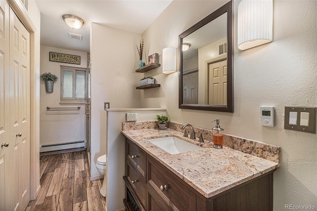 bathroom with a baseboard radiator, visible vents, toilet, vanity, and wood finished floors