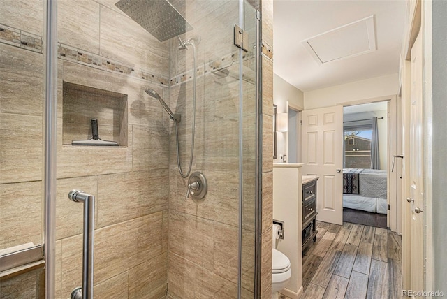 ensuite bathroom featuring toilet, wood finish floors, vanity, a stall shower, and ensuite bath