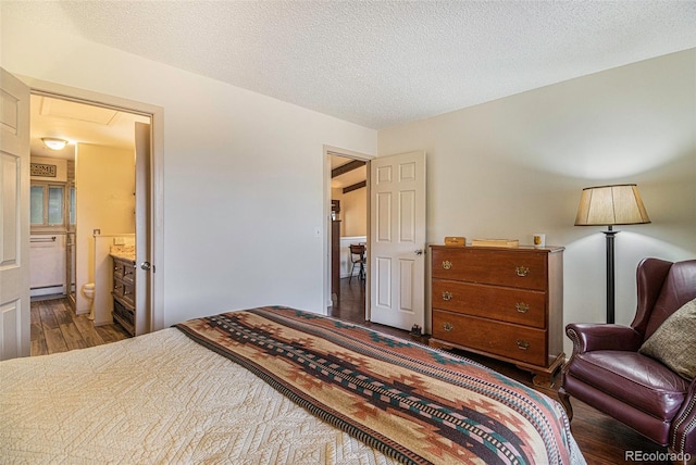 bedroom featuring attic access, a textured ceiling, ensuite bath, and wood finished floors