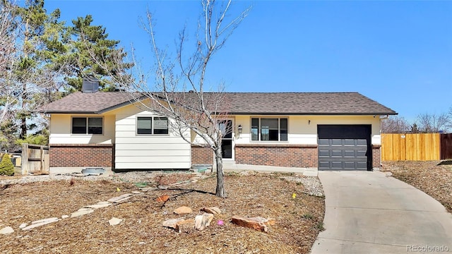 ranch-style home featuring driveway, fence, roof with shingles, a garage, and brick siding