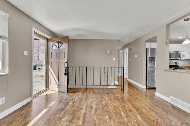 foyer entrance featuring visible vents, baseboards, and light wood finished floors