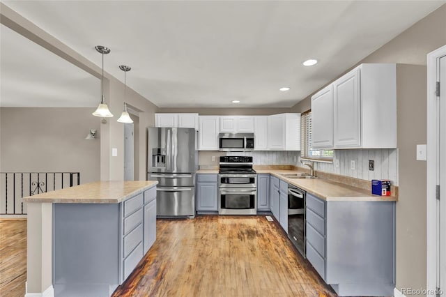 kitchen featuring light countertops, gray cabinets, appliances with stainless steel finishes, and a sink