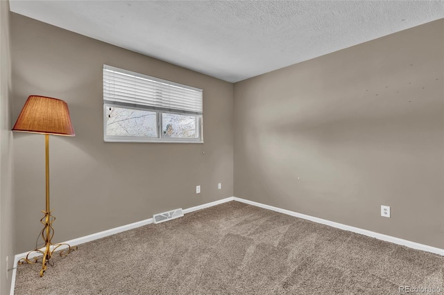 carpeted spare room with baseboards, visible vents, and a textured ceiling