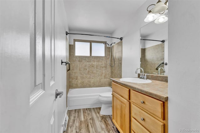 bathroom with washtub / shower combination, toilet, vanity, and wood finished floors