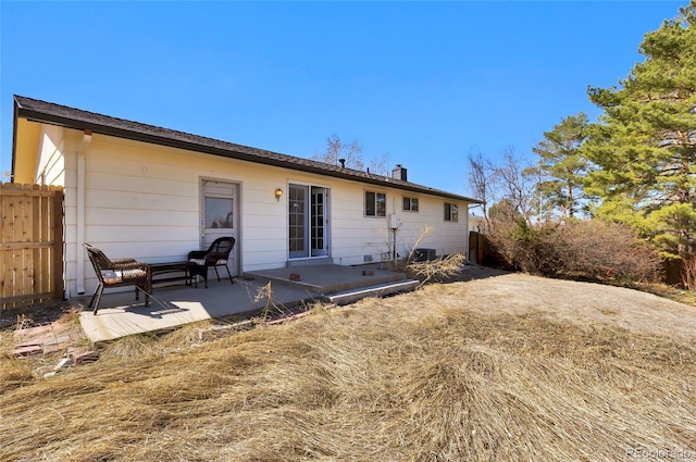 rear view of house featuring a patio area, a chimney, and fence