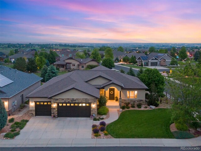 7992 Rising Sun Ct, Windsor, CO 80550 - view of front of house featuring an attached garage, concrete driveway, stone siding, a yard, and a residential view