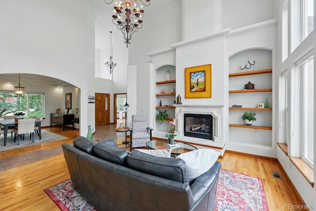 3 Desert Inn Way, Colorado Springs, CO 80921 - living area featuring a chandelier, a towering ceiling, built in shelves, arched walkways, and a glass covered fireplace