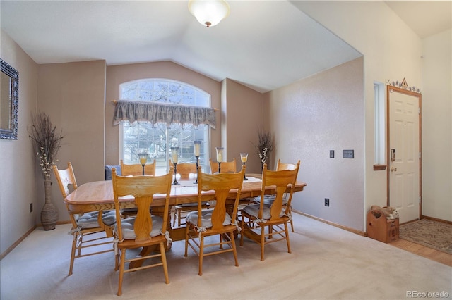 dining area with lofted ceiling, baseboards, and light colored carpet