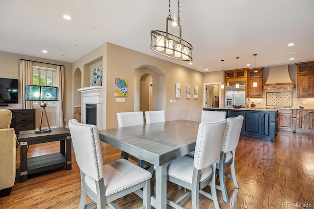 8526 E 35th Ave, Denver, CO 80238 - dining room featuring wood finished floors, arched walkways, recessed lighting, a fireplace, and a chandelier