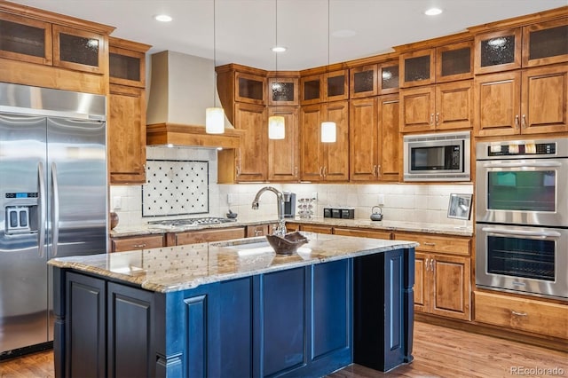 8526 E 35th Ave, Denver, CO 80238 - kitchen featuring built in appliances, light wood-type flooring, premium range hood, an island with sink, and recessed lighting