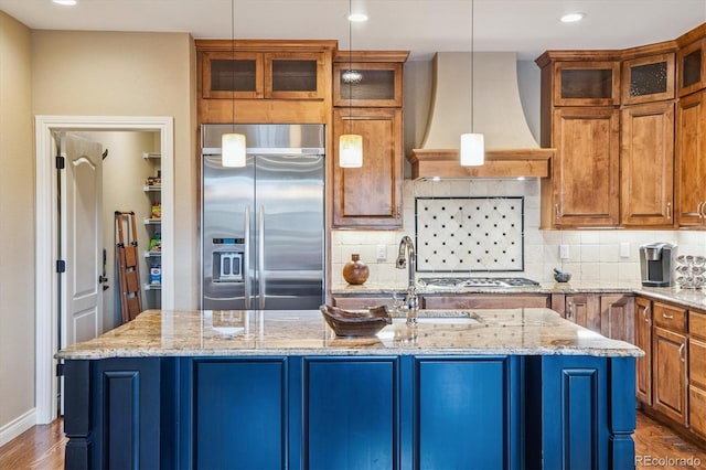 8526 E 35th Ave, Denver, CO 80238 - kitchen featuring appliances with stainless steel finishes, custom range hood, a center island with sink, tasteful backsplash, and brown cabinets