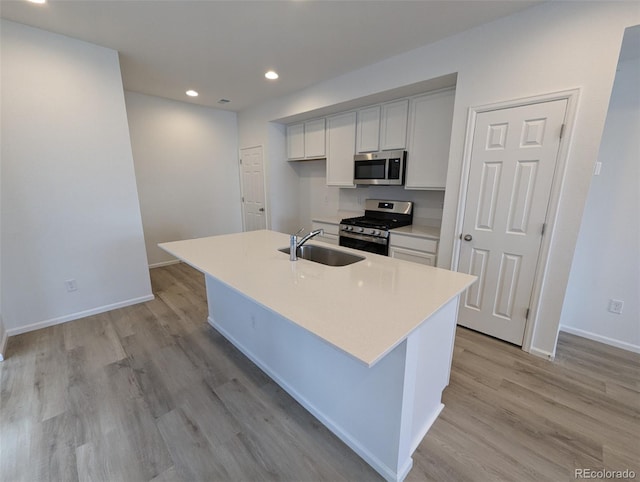 kitchen featuring sink, an island with sink, stainless steel appliances, and light hardwood / wood-style floors